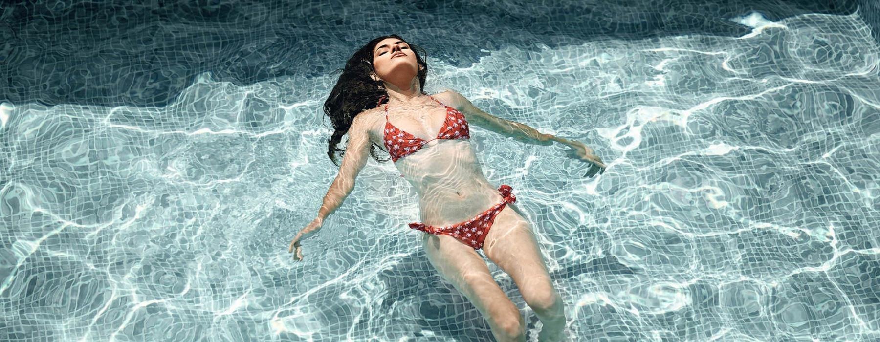 woman floats on her back in swimming pool